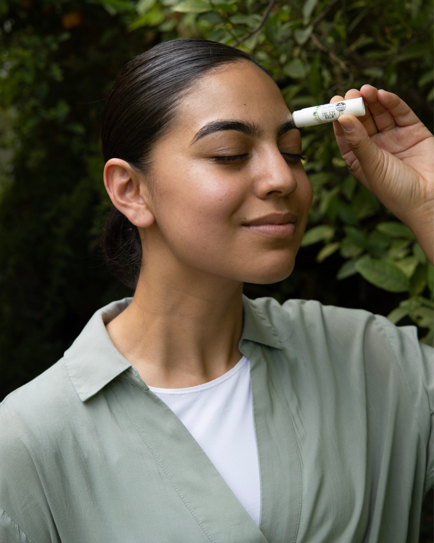 A woman applies The Eye Balm™ to her eyebrows.